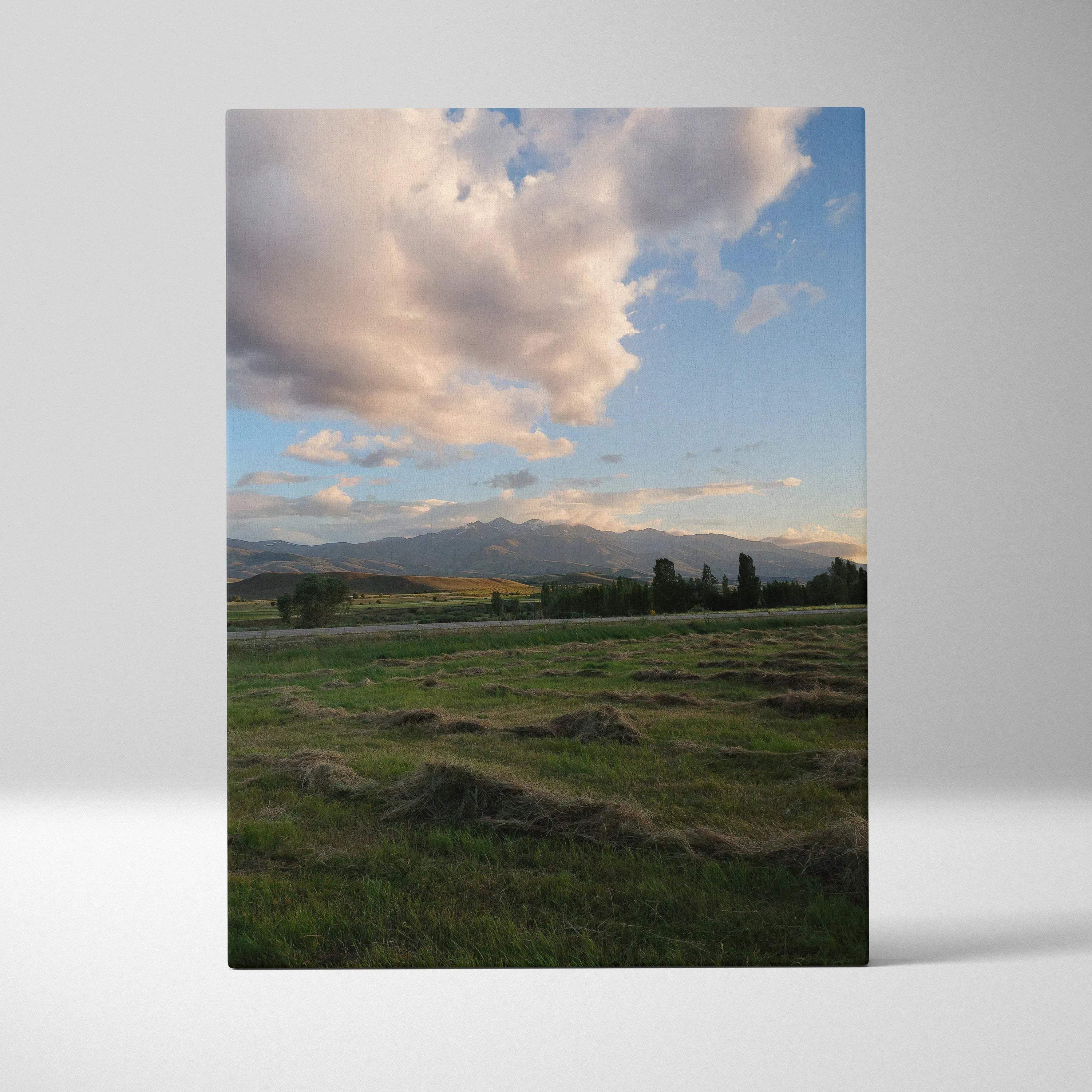 Vertical canvas wall art featuring a serene mountain landscape under a dramatic cloudy sunset sky.