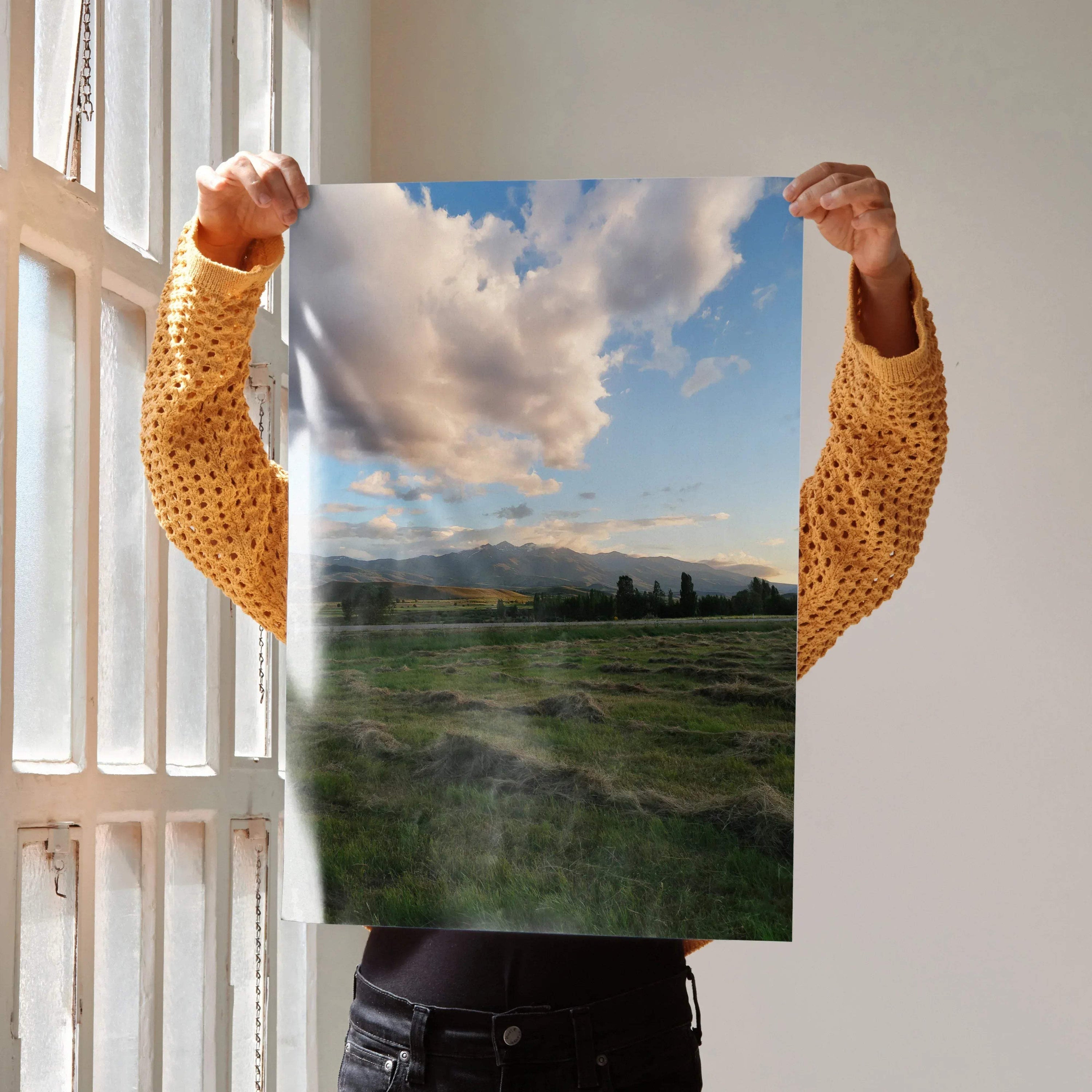 Vertical wall art poster featuring a vibrant mountain sunset over green fields and cloudy sky.