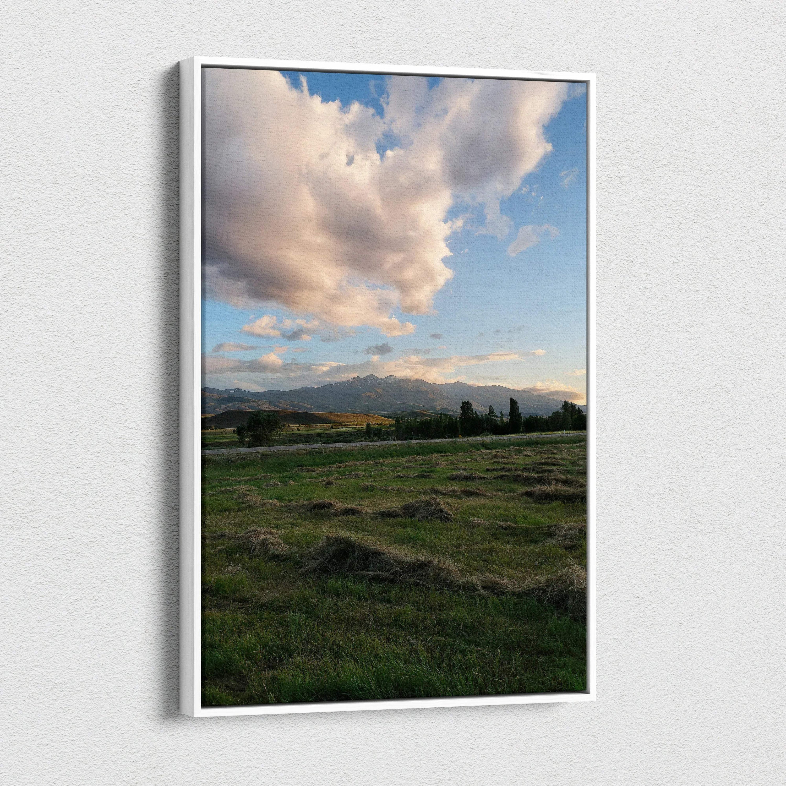 Vertical canvas wall art featuring a mountain sunset with dramatic clouds over a green field.