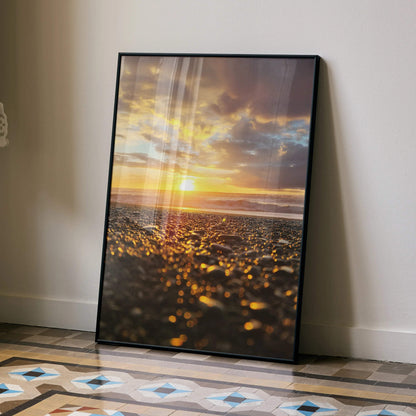 Ocean sunset beach poster with golden sunlight and dark clouds, vertical wall art in black frame.