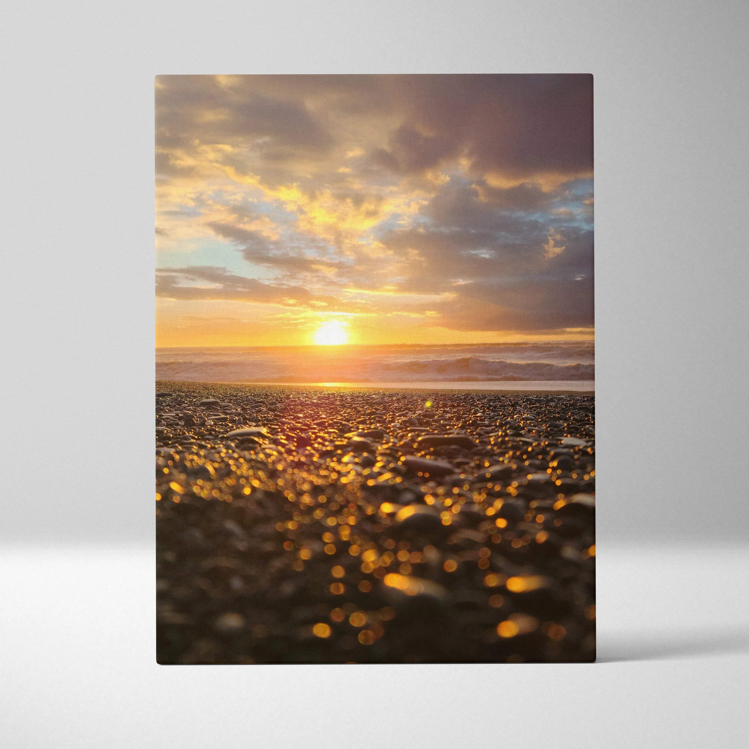 Canvas wall art featuring a vibrant beach sunset with golden sunlight reflecting on pebbled shore.