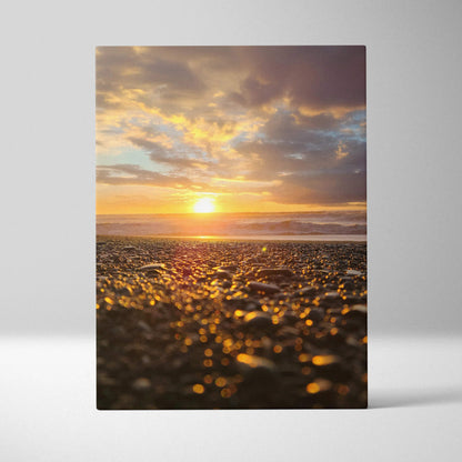 Canvas wall art featuring a vibrant beach sunset with golden sunlight reflecting on pebbled shore.