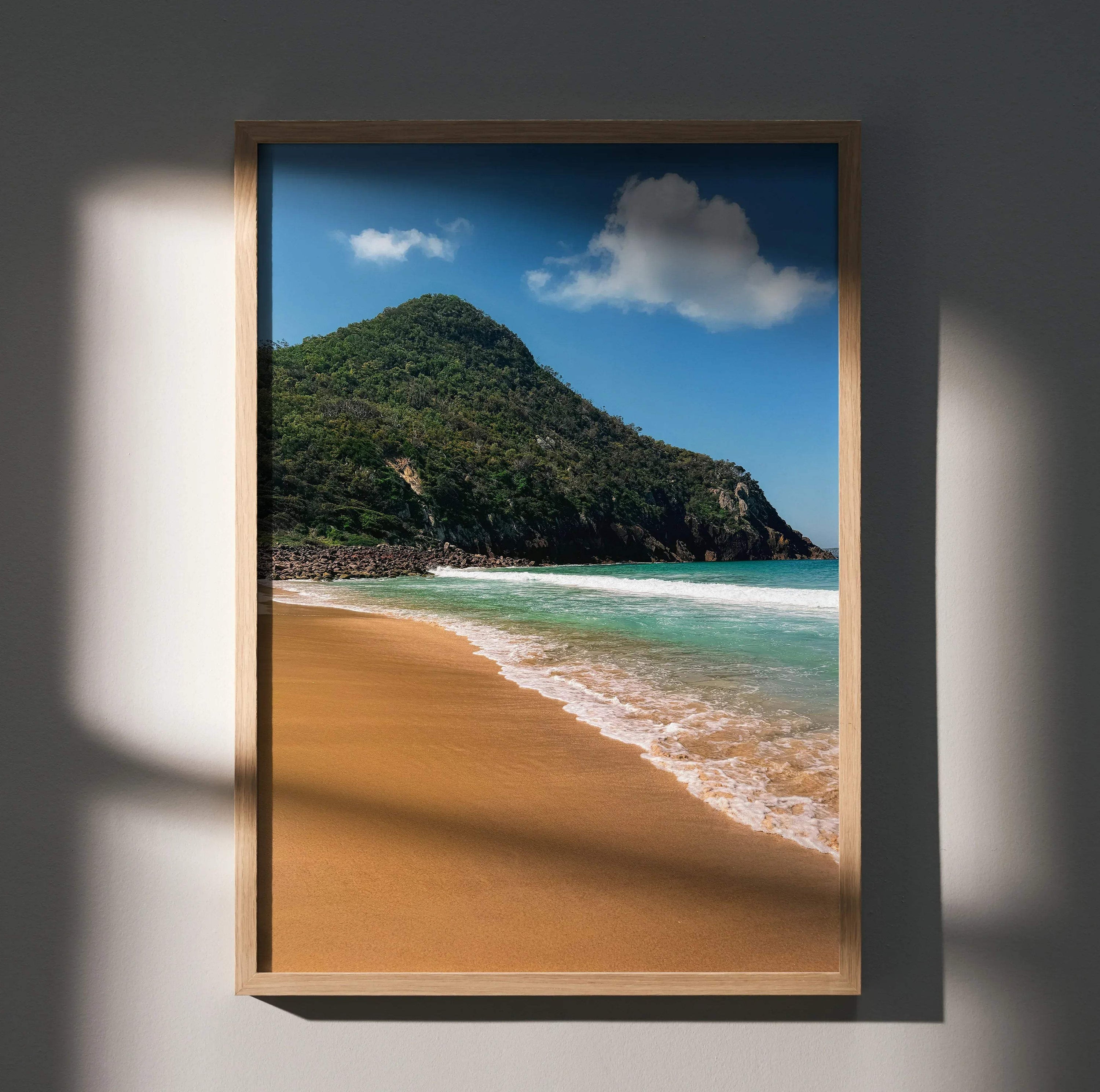 Serene beach wall art poster featuring sandy shore, turquoise ocean waves, and green hillside under blue sky.