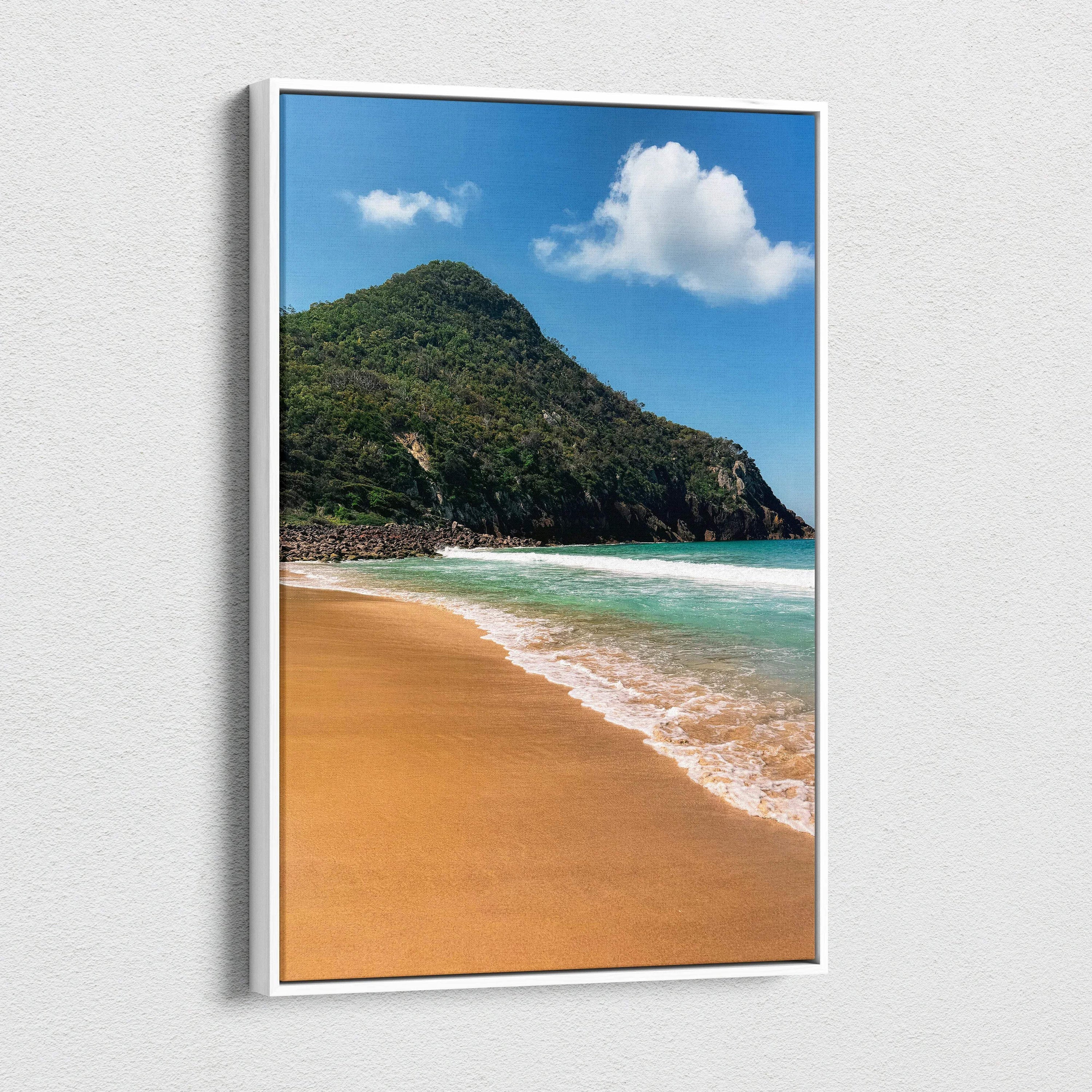 Vertical canvas wall art of a sandy beach with turquoise water and lush green mountain beneath a blue sky with clouds.