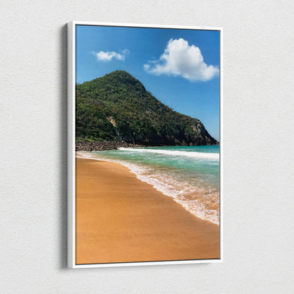 Vertical canvas wall art of a sandy beach with turquoise water and lush green mountain beneath a blue sky with clouds.