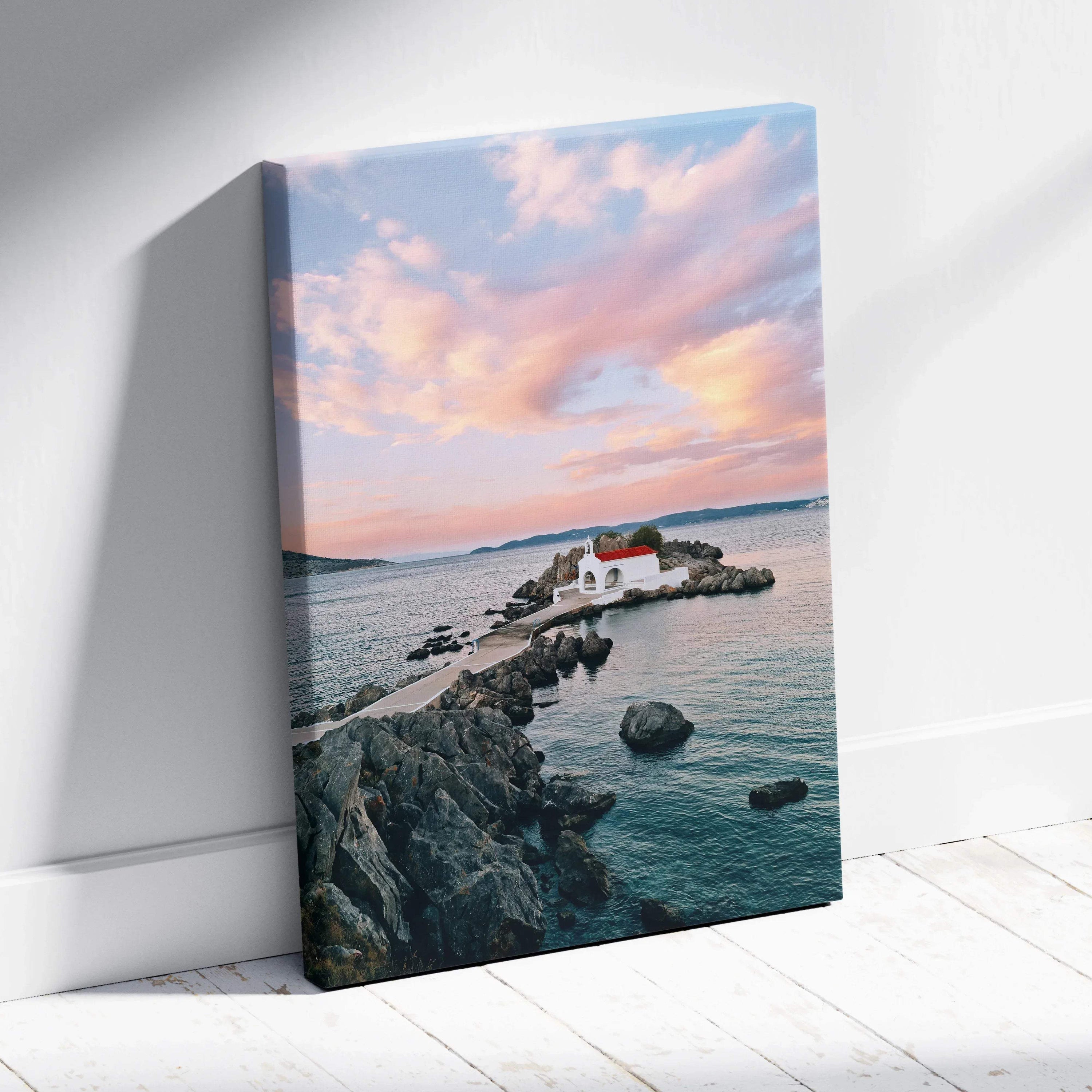 Sunset beach scene with rocky pier and white buildings on canvas wall art.