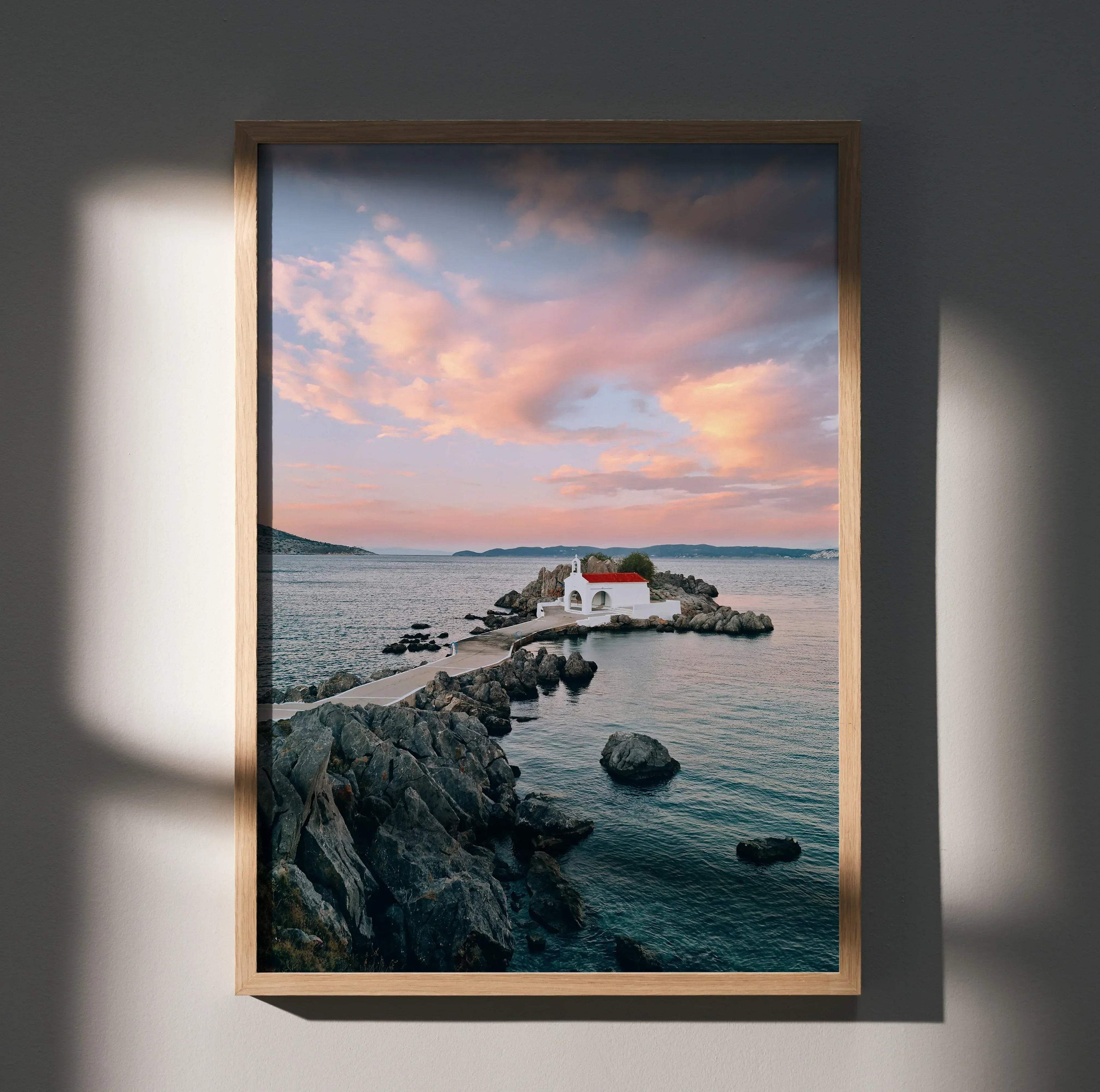Vertical beach sunset wall art poster featuring a rocky shore and a small white house with a red roof.