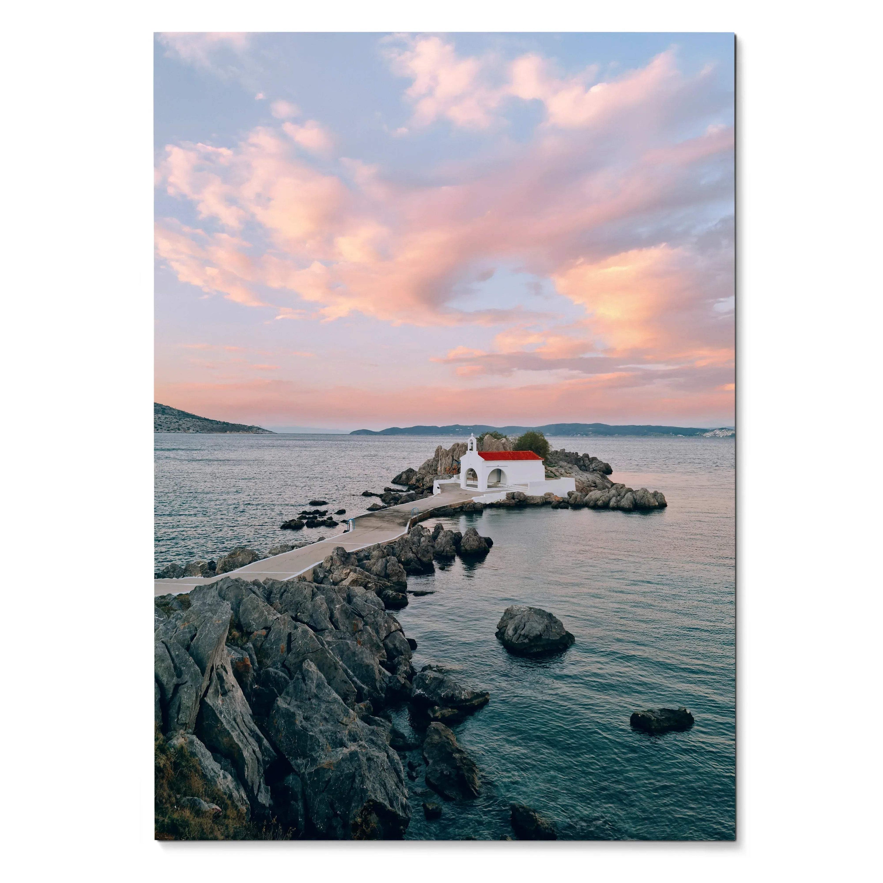 Vertical poster of beach sunset with pink clouds over small white house on rocky shore wall art.