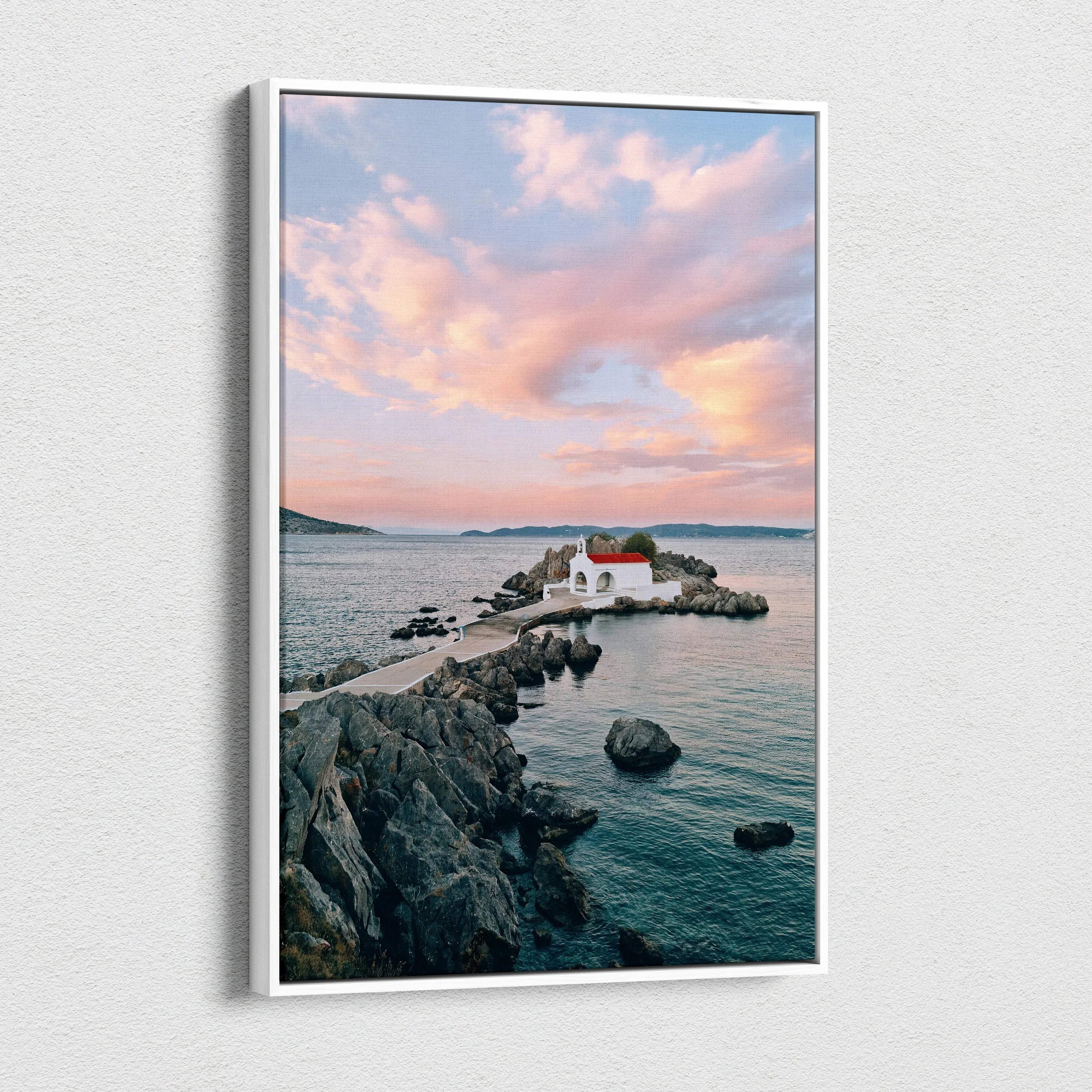 Canvas wall art featuring serene sunset over rocky coastline with small white building and calm water.