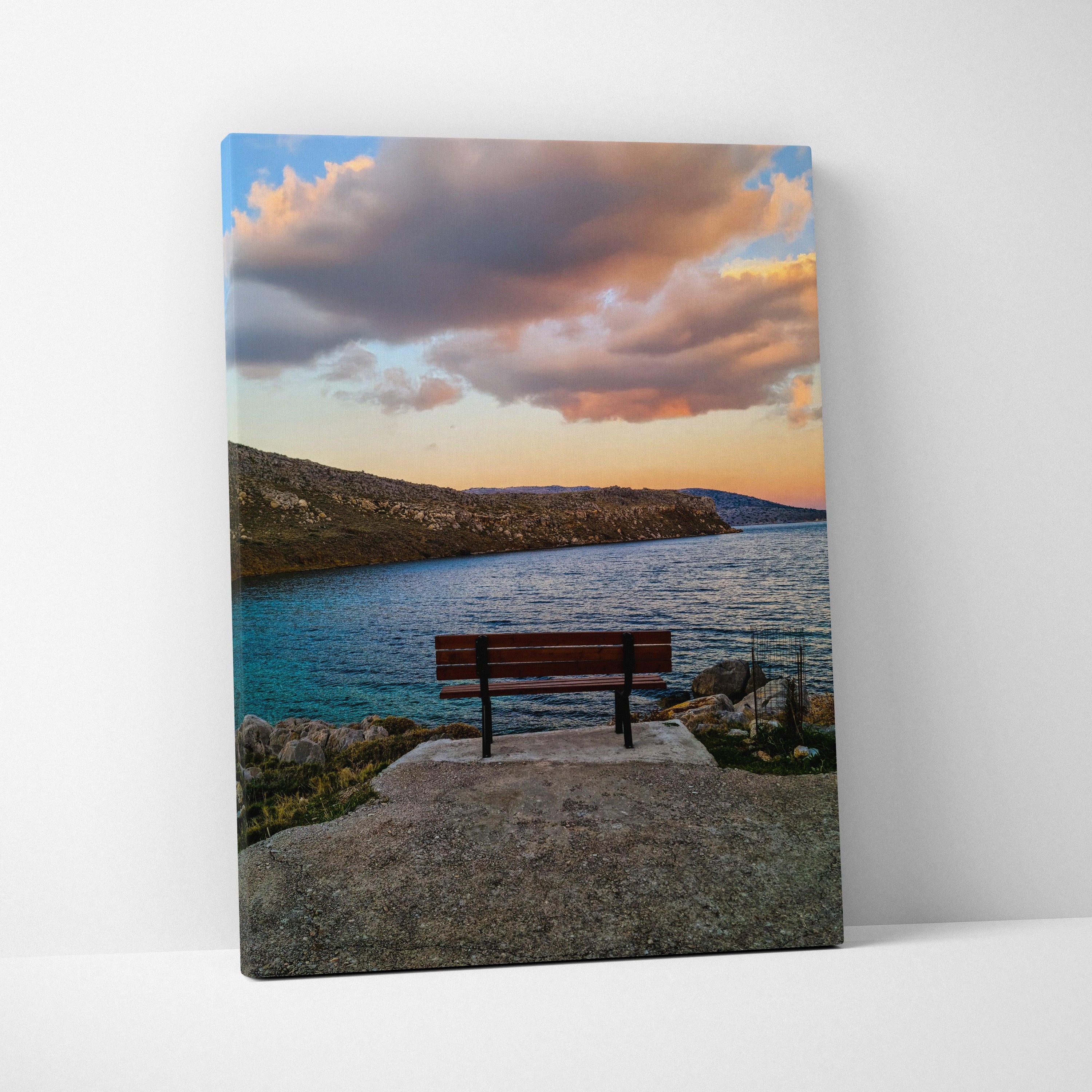 Canvas wall art featuring a sunset over a calm bay with a lone bench on a rocky pier.