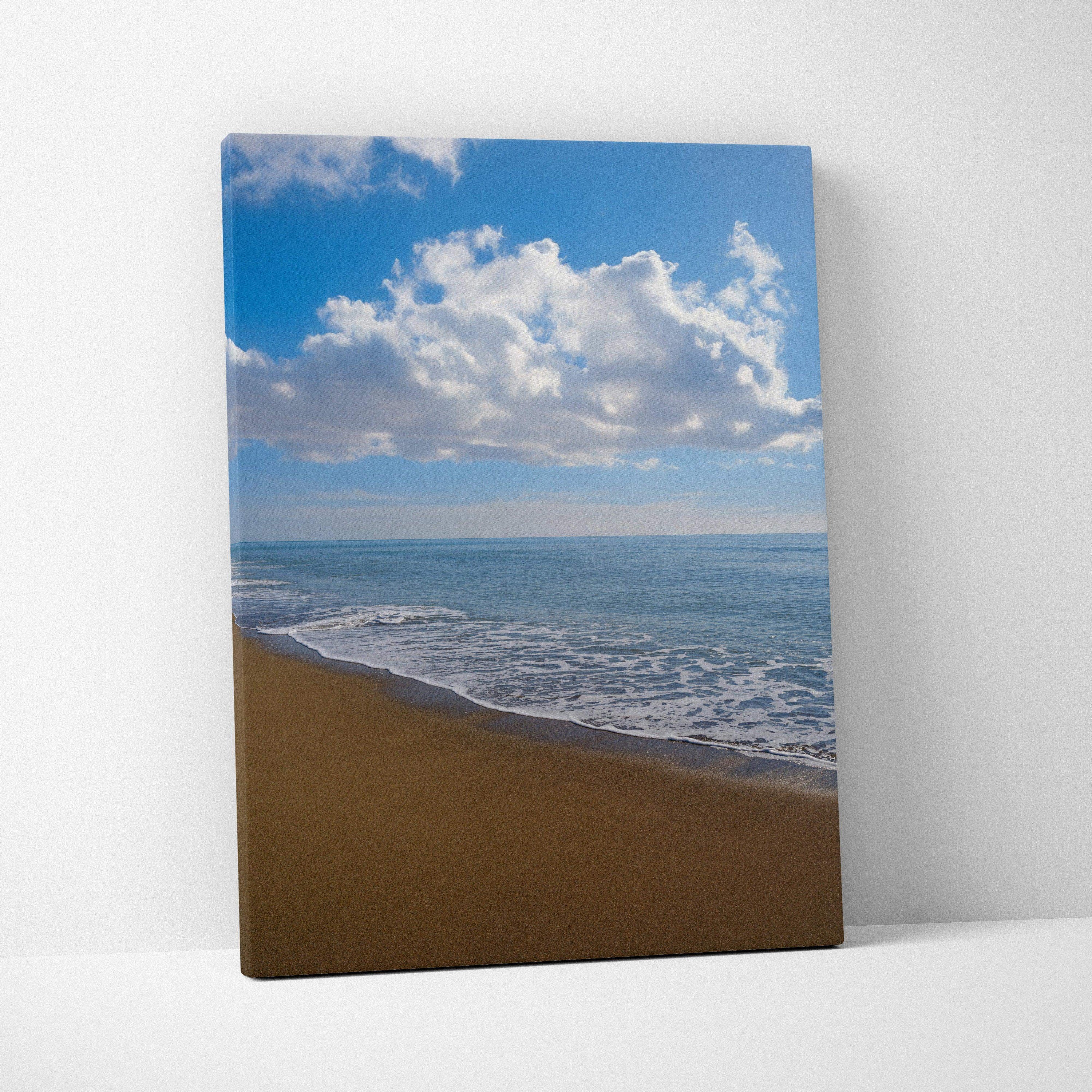 Canvas wall art featuring a serene beach with gentle waves and a bright blue sky with clouds.