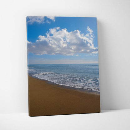 Canvas wall art featuring a serene beach with gentle waves and a bright blue sky with clouds.