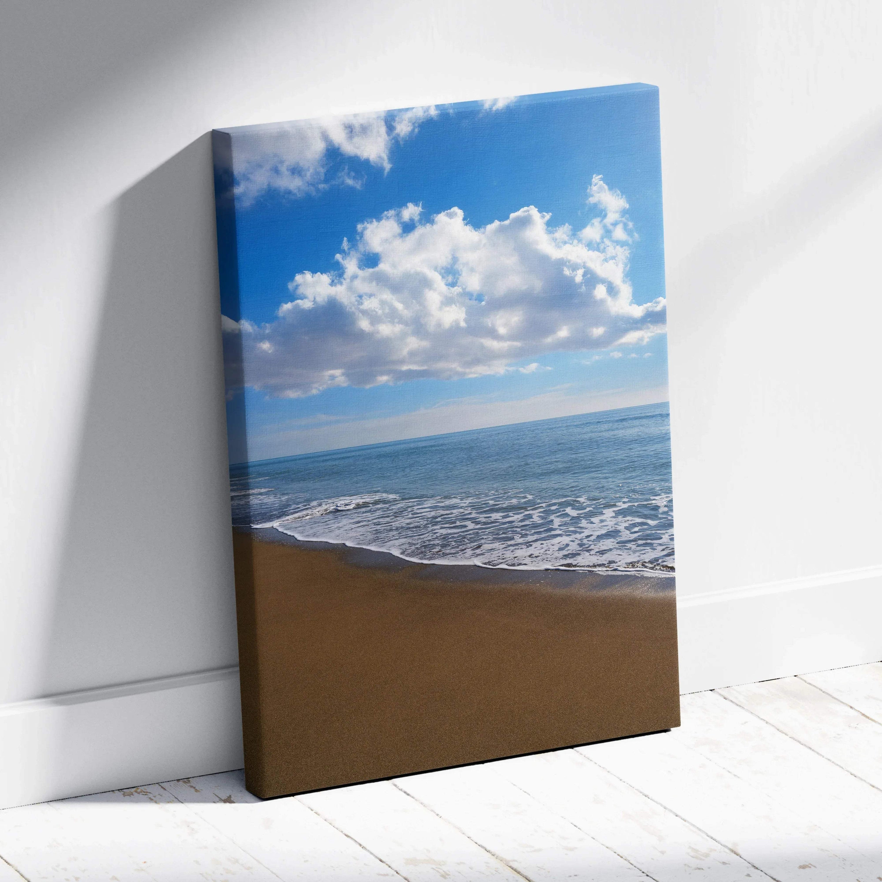 Canvas wall art featuring a serene beach with golden sand, calm waves, and a bright blue sky with fluffy clouds.