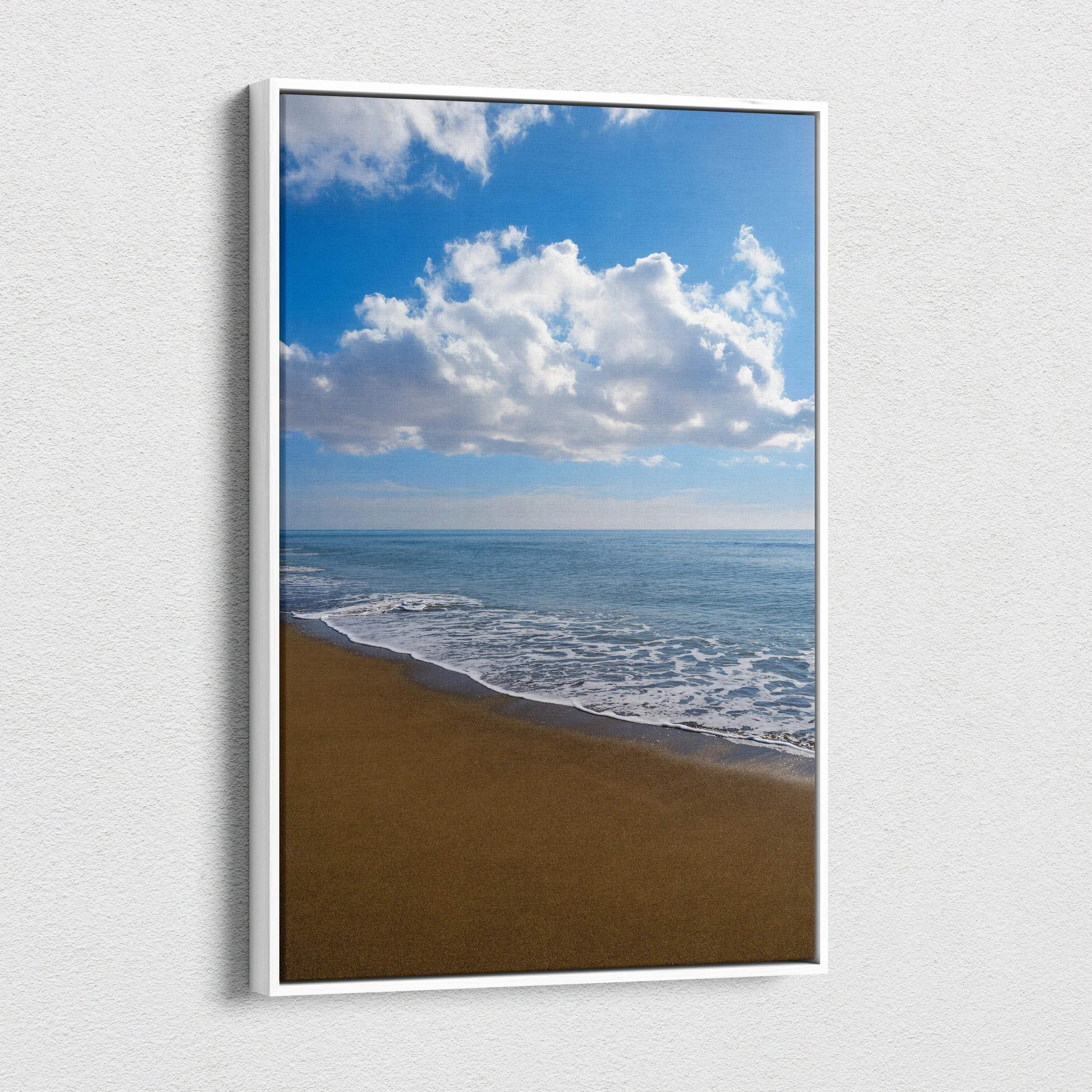 Vertical canvas wall art depicting a serene beach with gentle waves and blue sky with clouds.