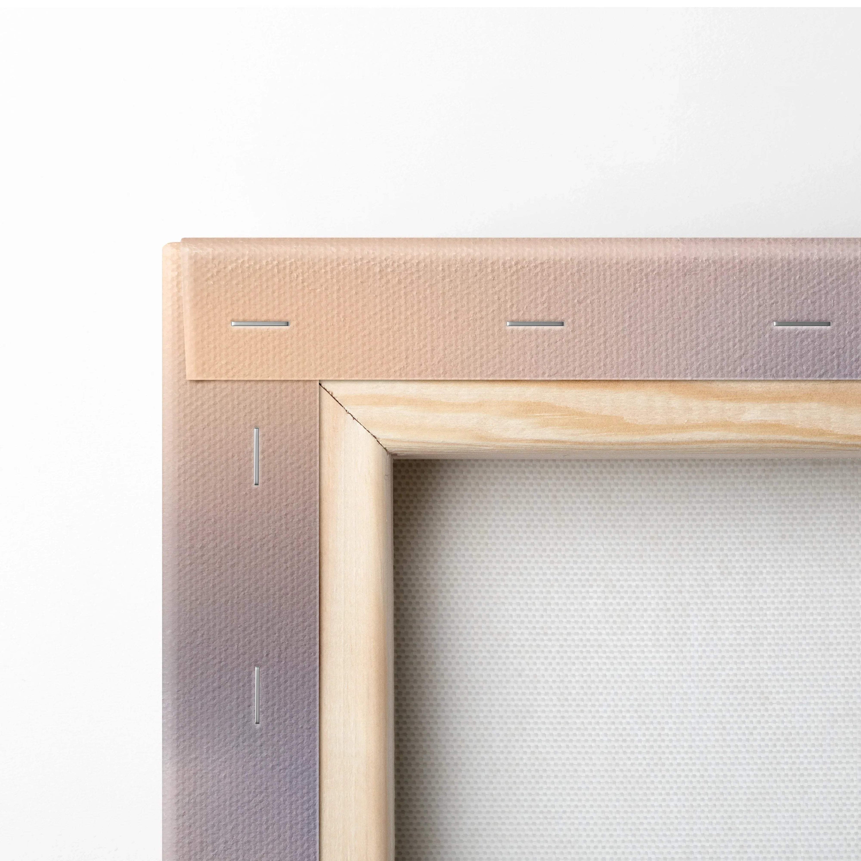 Close-up of wooden frame corner and stapled beige canvas backing on wall art print.