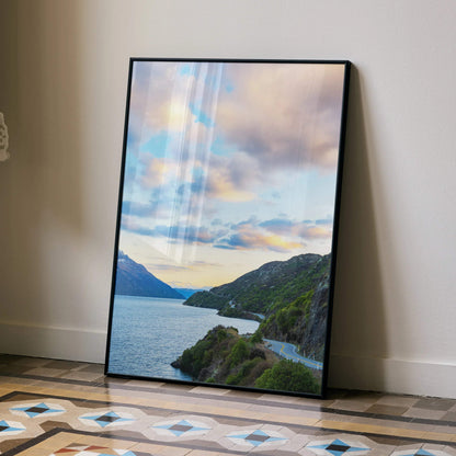 Vertical poster wall art featuring vibrant mountains and a colorful sunset sky over a winding lakeside road.