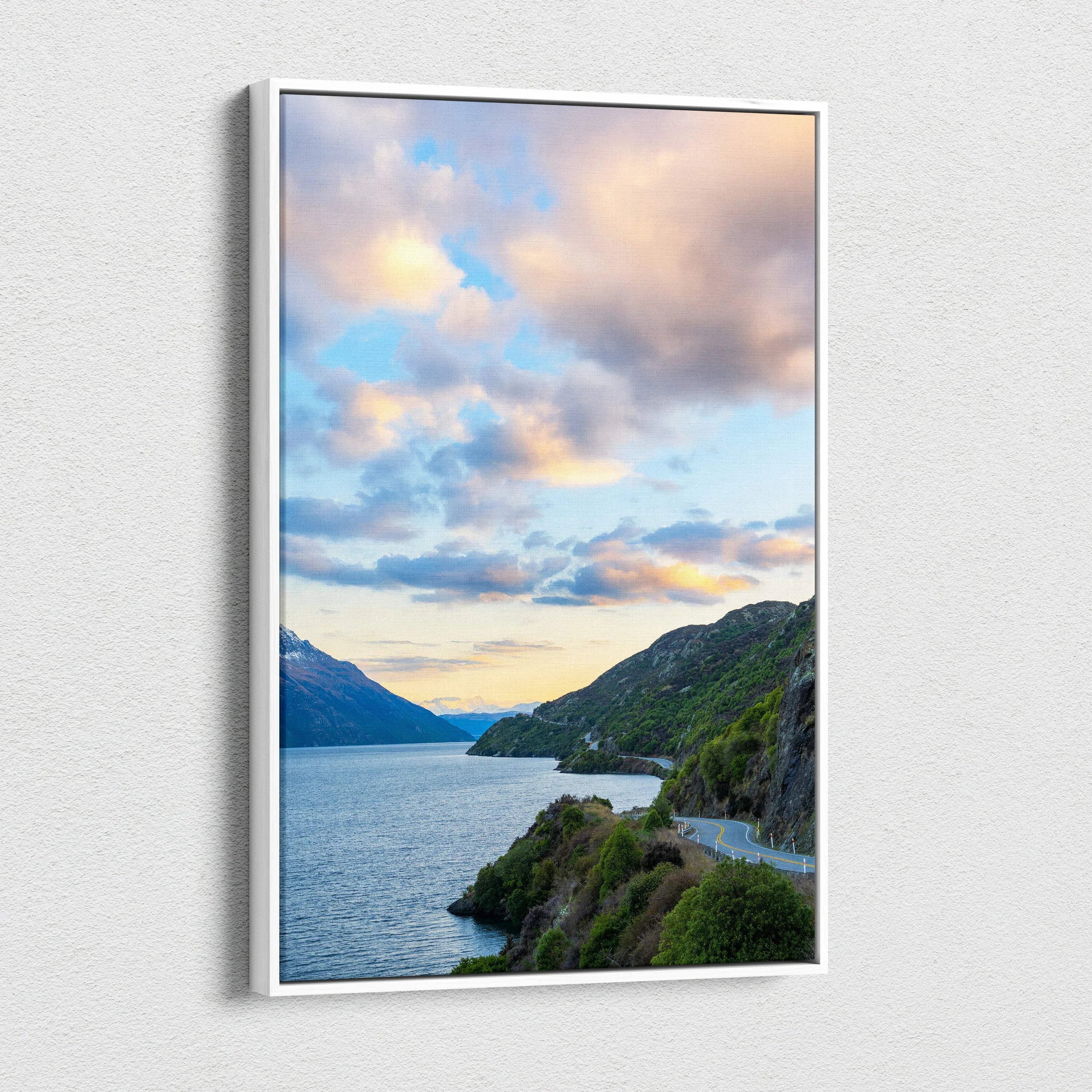 Vertical canvas wall art showcasing a mountain lake at sunset with colorful clouds and green hills.