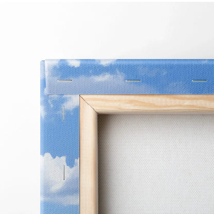 Corner detail of stretched canvas with blue sky and white cloud print on wooden frame for wall art.