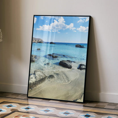 Vertical beach landscape poster with clear blue water, rocks, and sandy shore wall art.
