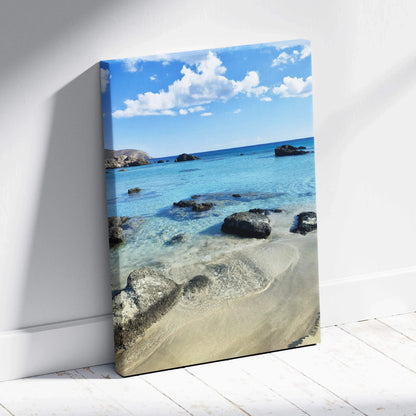 Canvas wall art featuring a serene beach scene with clear blue water and scattered rocks.