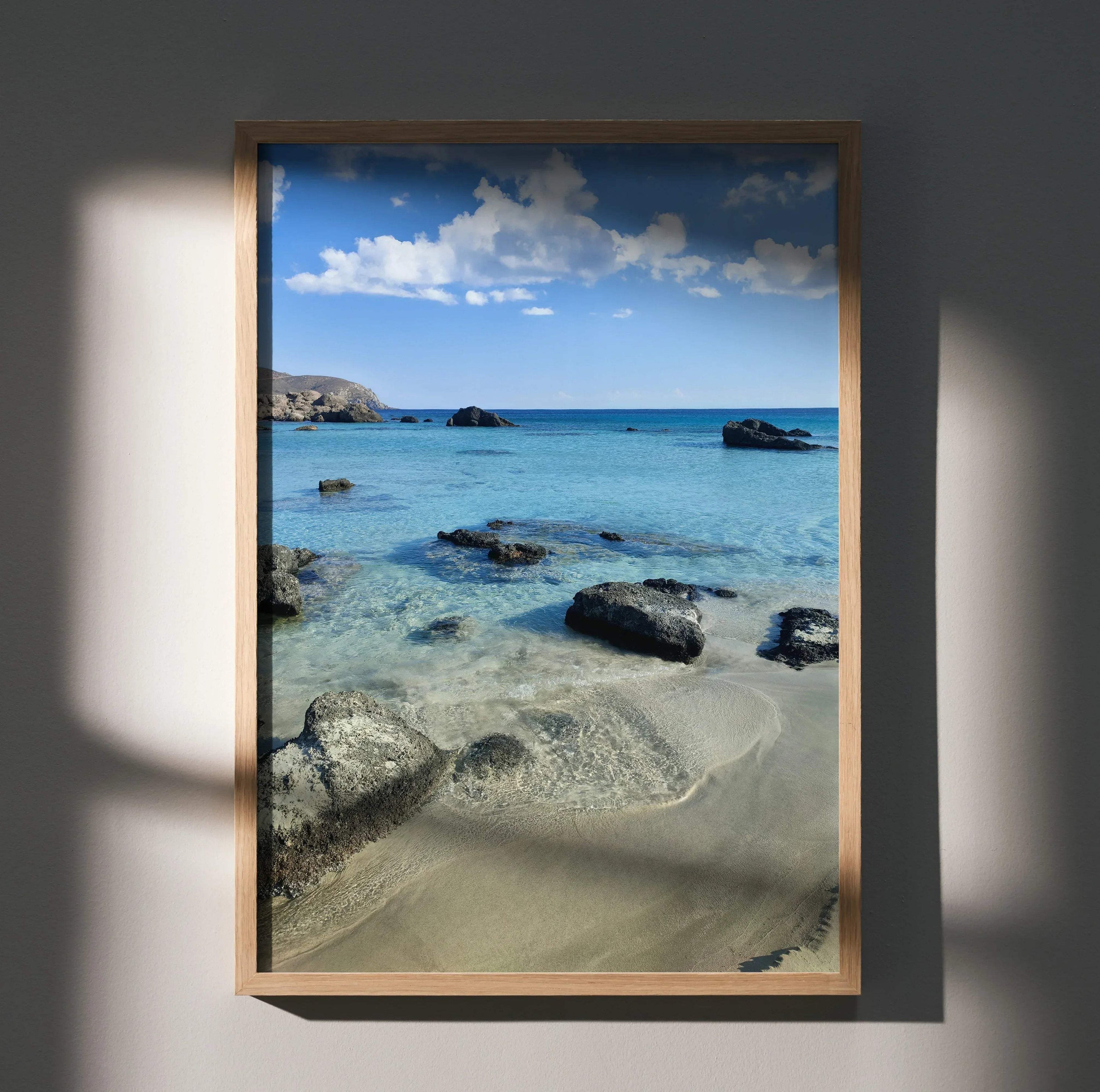 Vertical beach landscape poster with clear turquoise water, scattered rocks, and blue sky wall art.