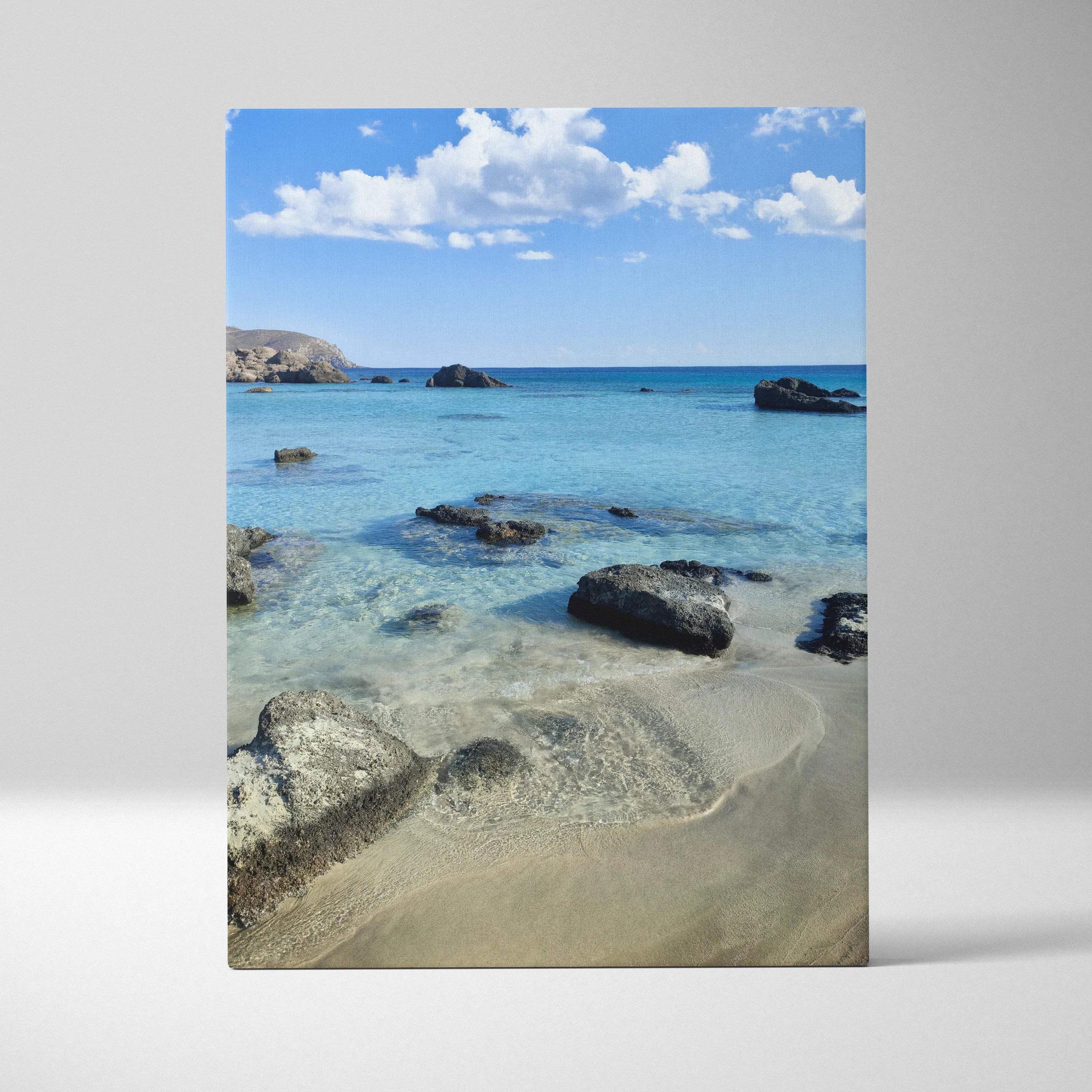 Canvas wall art featuring a serene beach scene with clear blue water, rocks, and sandy shore under a bright sky.