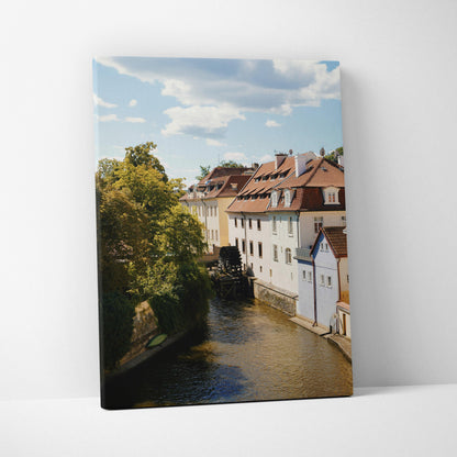 Canvas wall art featuring charming urban canal scene with historic buildings and lush greenery under a blue sky.