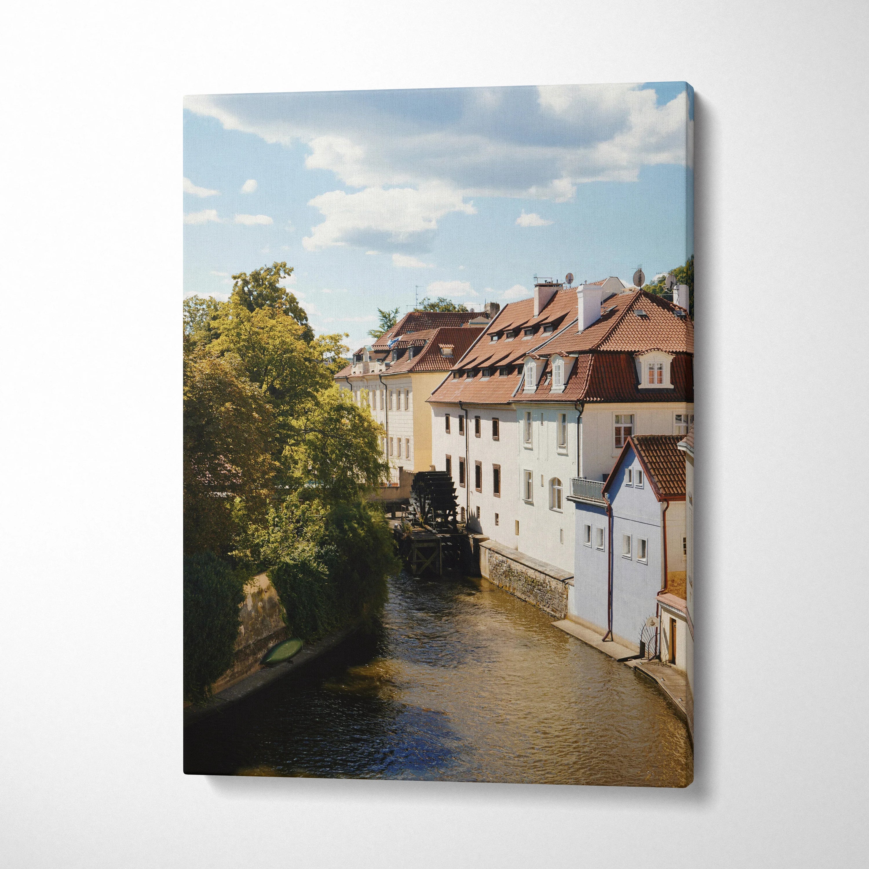 Canvas wall art print of a peaceful urban canal with traditional buildings and leafy trees under a blue sky.