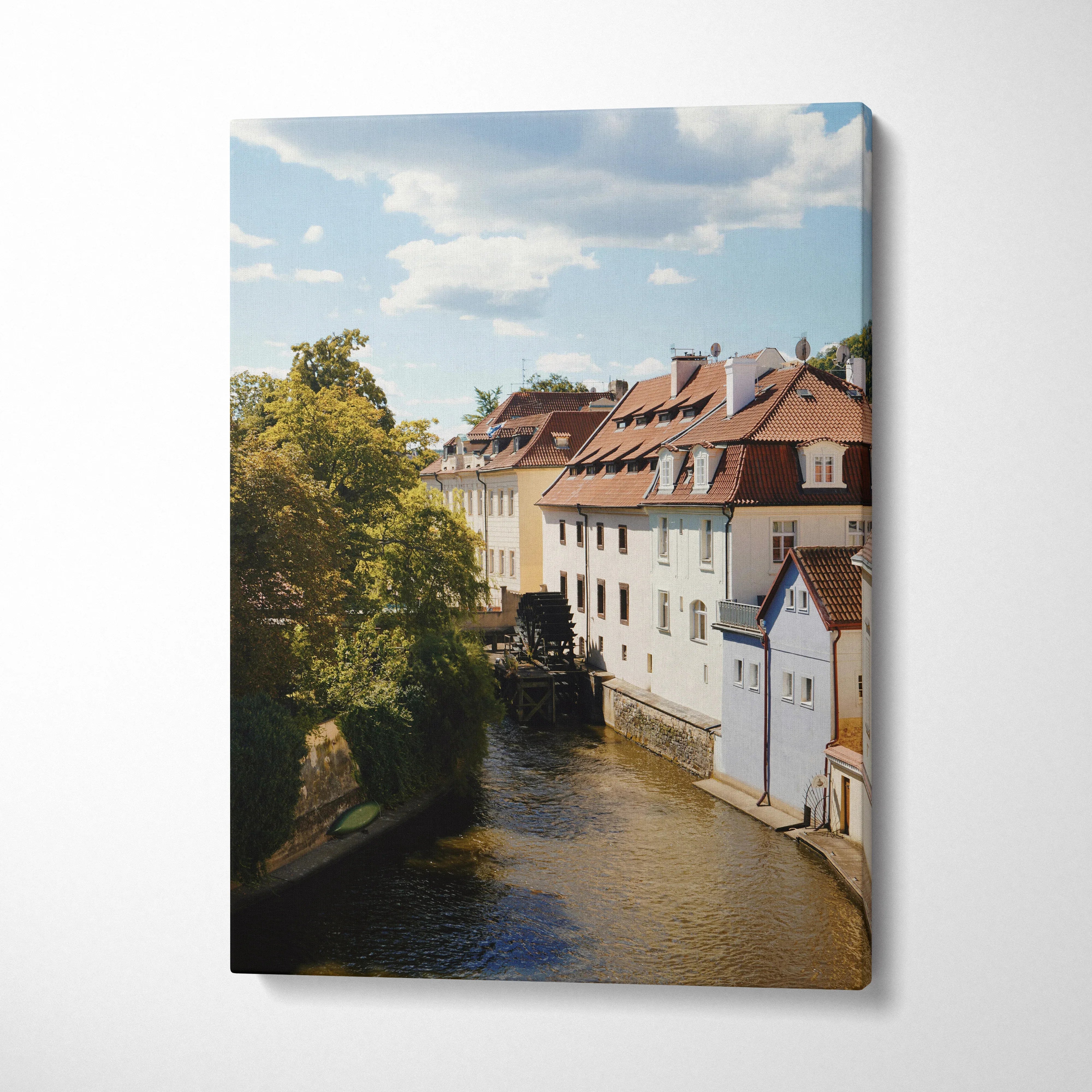 Canvas wall art print of a peaceful urban canal with traditional buildings and leafy trees under a blue sky.