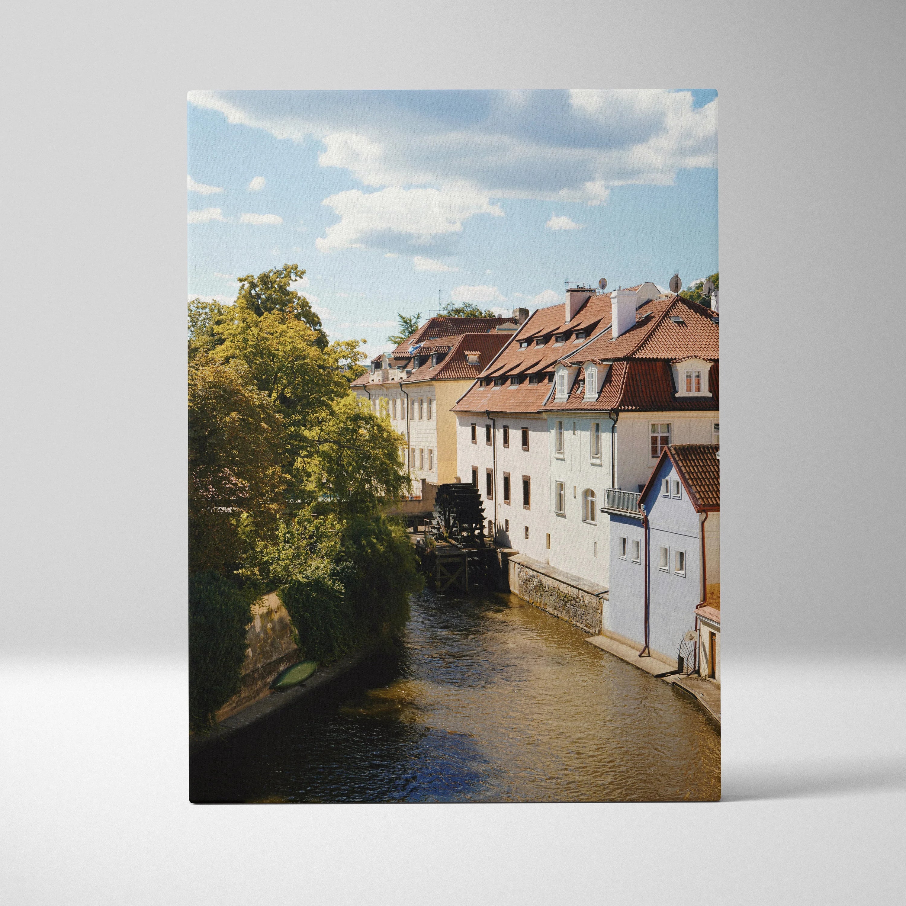 Canvas wall art featuring a serene urban canal with traditional buildings and lush greenery under a blue sky.