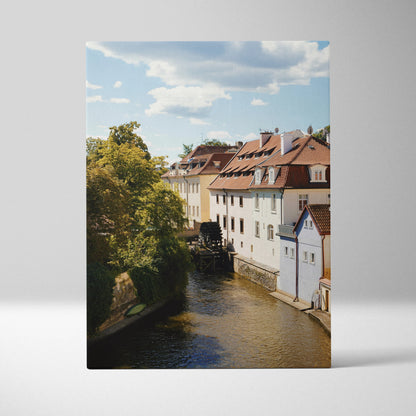 Canvas wall art featuring a serene urban canal with traditional buildings and lush greenery under a blue sky.
