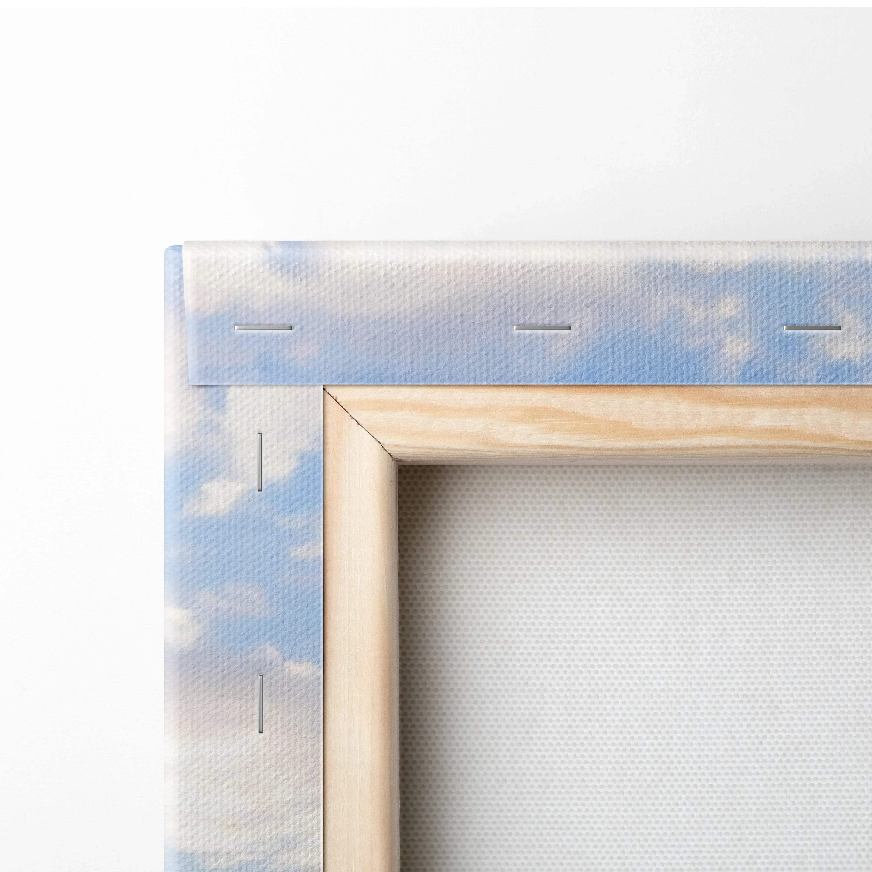 Close-up of wooden frame and canvas backing with soft blue sky and cloud print, wall art detail.