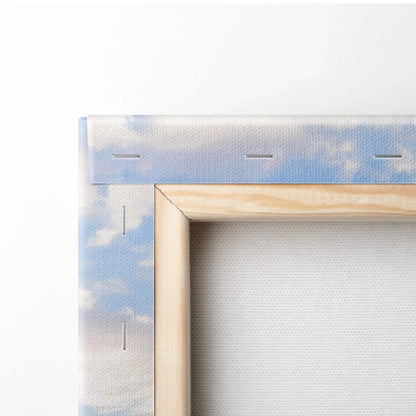 Close-up of wooden frame and canvas backing with soft blue sky and cloud print, wall art detail.