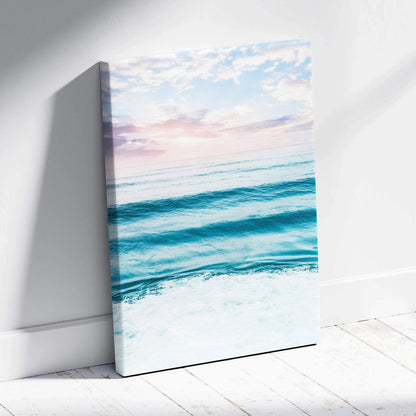 Sunset over calm blue ocean waves on vertical canvas wall art with soft pastel sky.