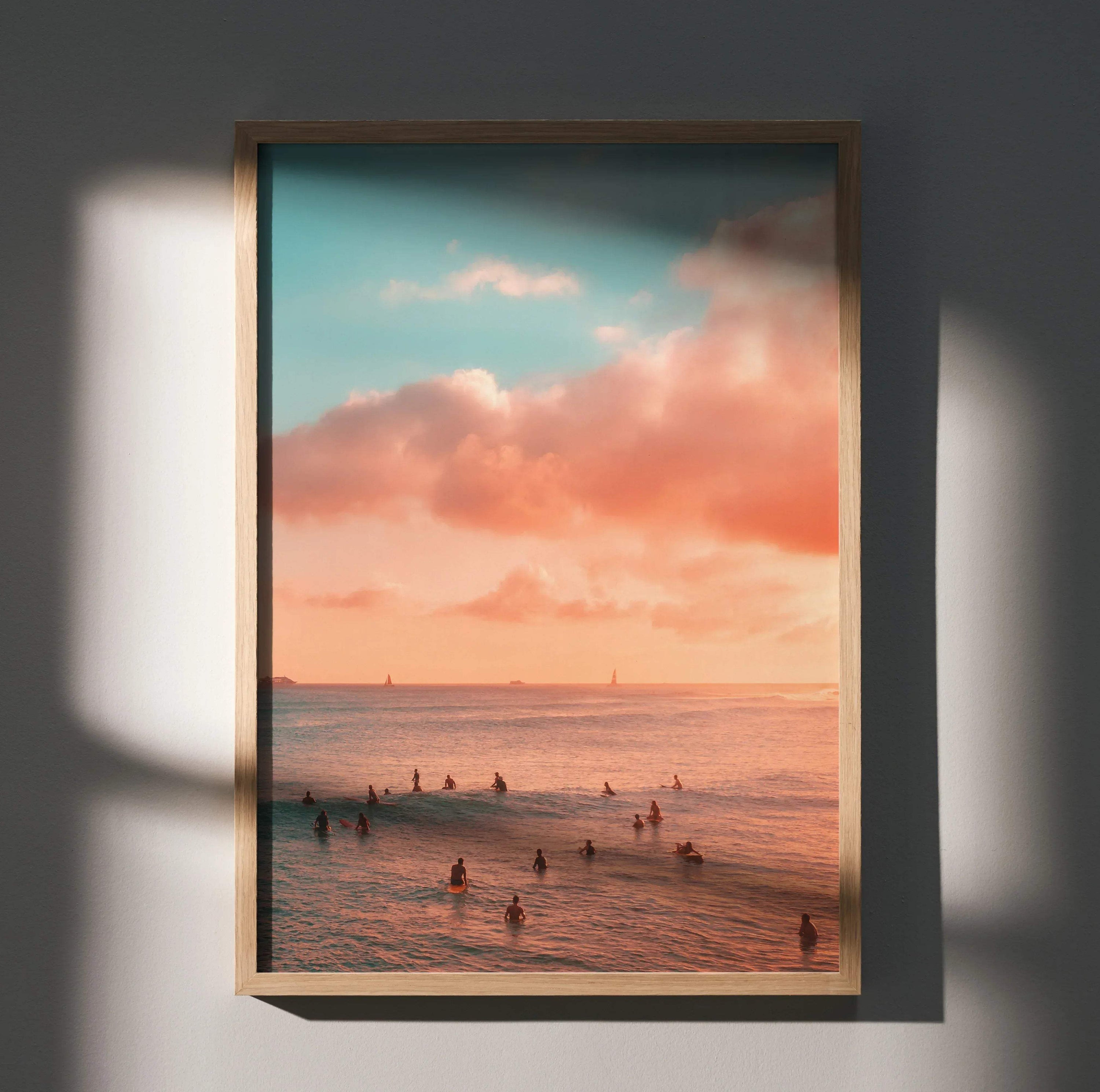 Vertical wall art poster of a serene ocean sunset with surfers silhouetted in the water and colorful sky.