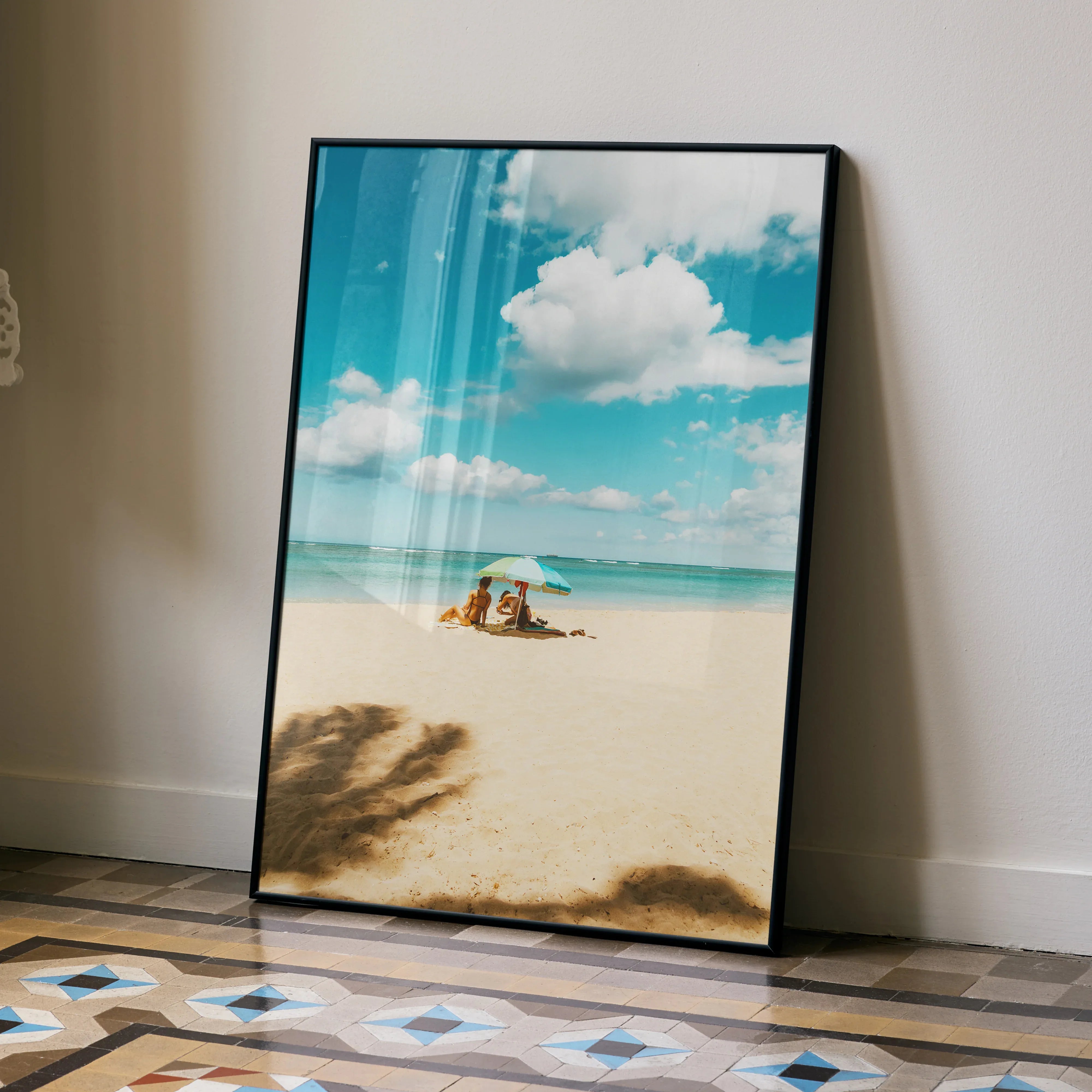 Vertical wall art poster of a serene beach with soft sand, bright blue sky, and white clouds.