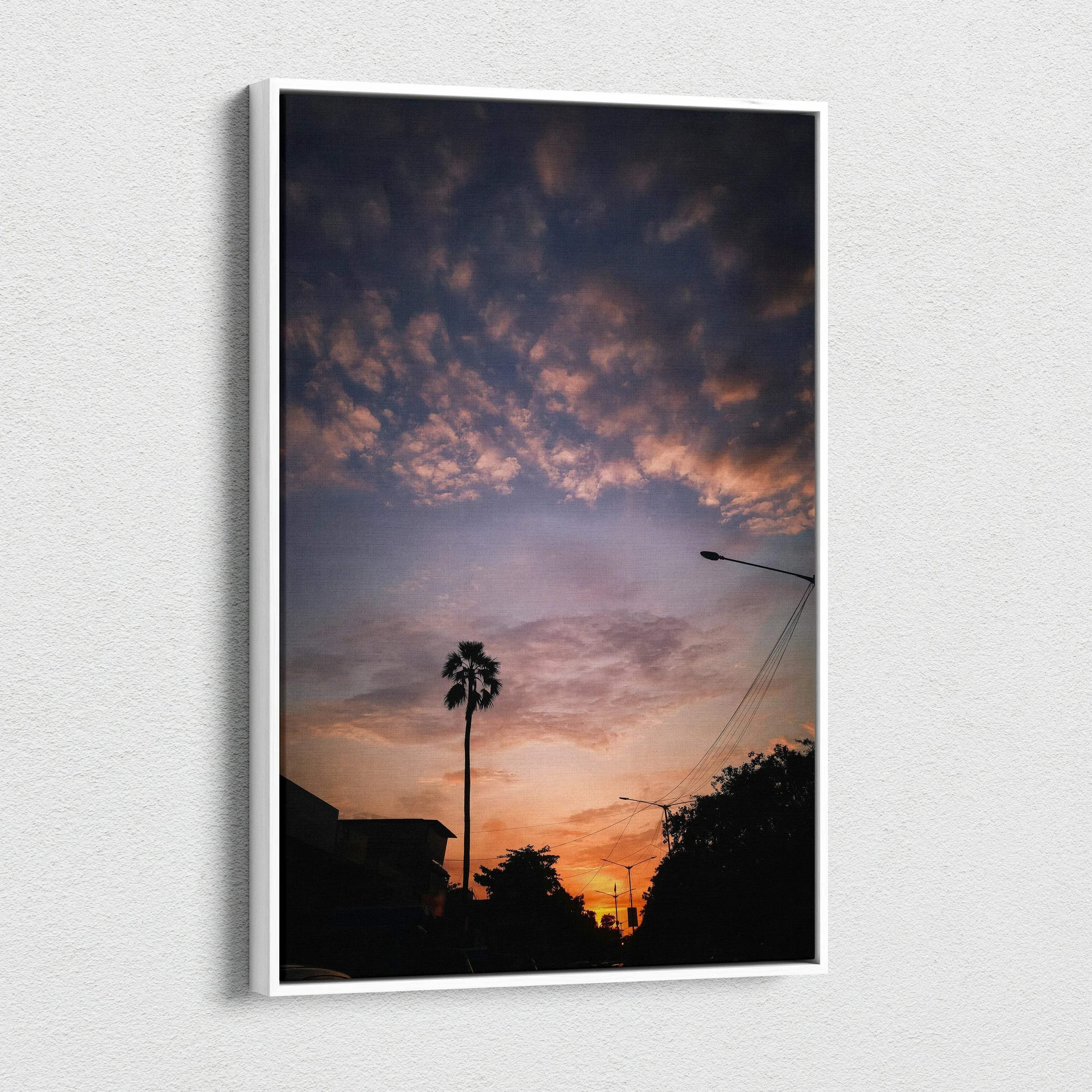 Vertical canvas wall art of vibrant sunset sky with silhouetted palm tree and rooftops.