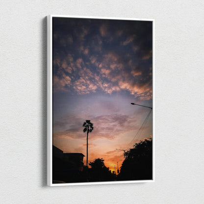 Vertical canvas wall art of vibrant sunset sky with silhouetted palm tree and rooftops.