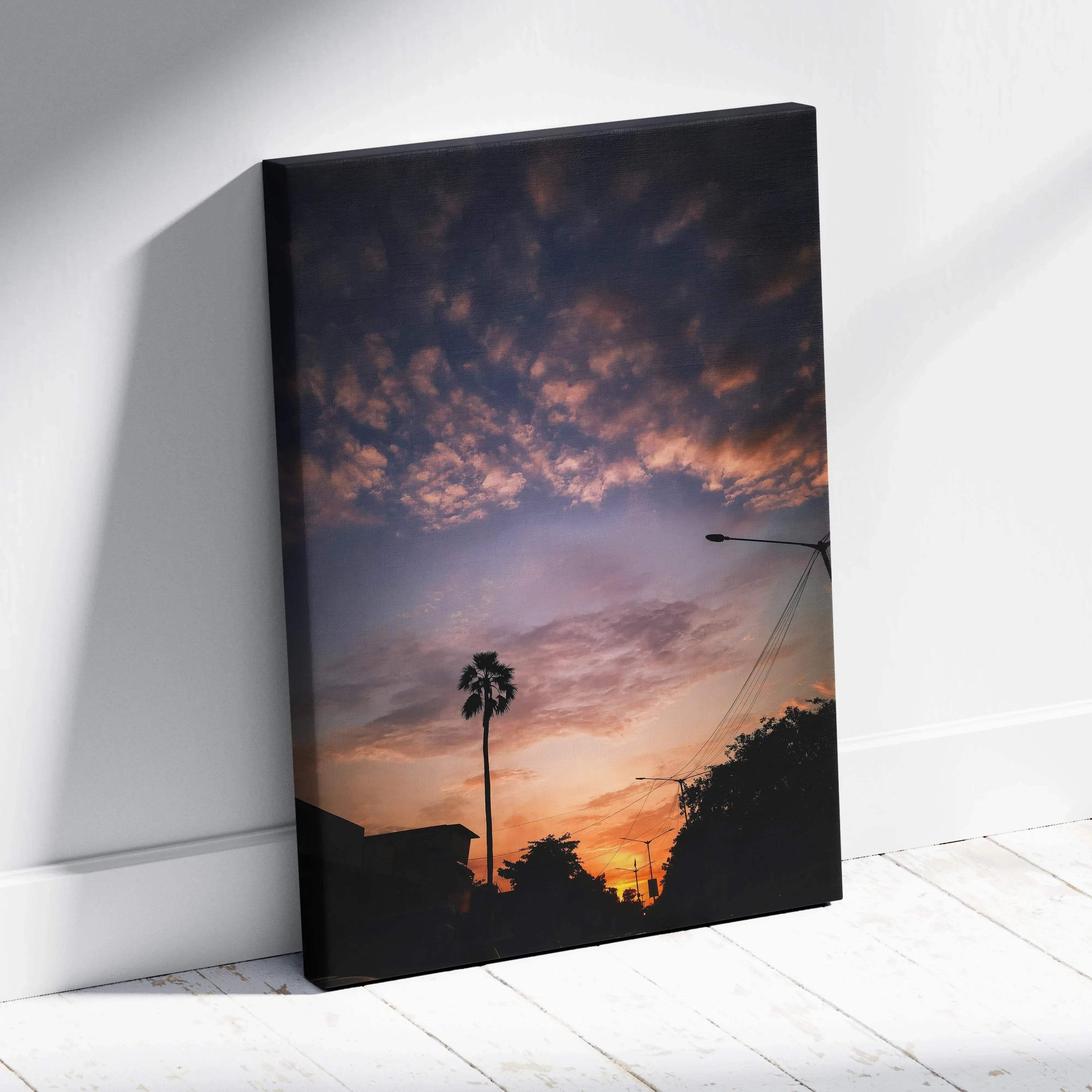 Vertical canvas wall art featuring a vibrant sunset sky with silhouetted palm tree and rooftops.