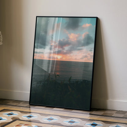 Ocean sunset with pink and blue clouds over calm water, vertical wall art poster with black frame.