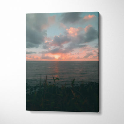 Sunset over calm ocean with clouds and silhouetted shoreline on canvas wall art.