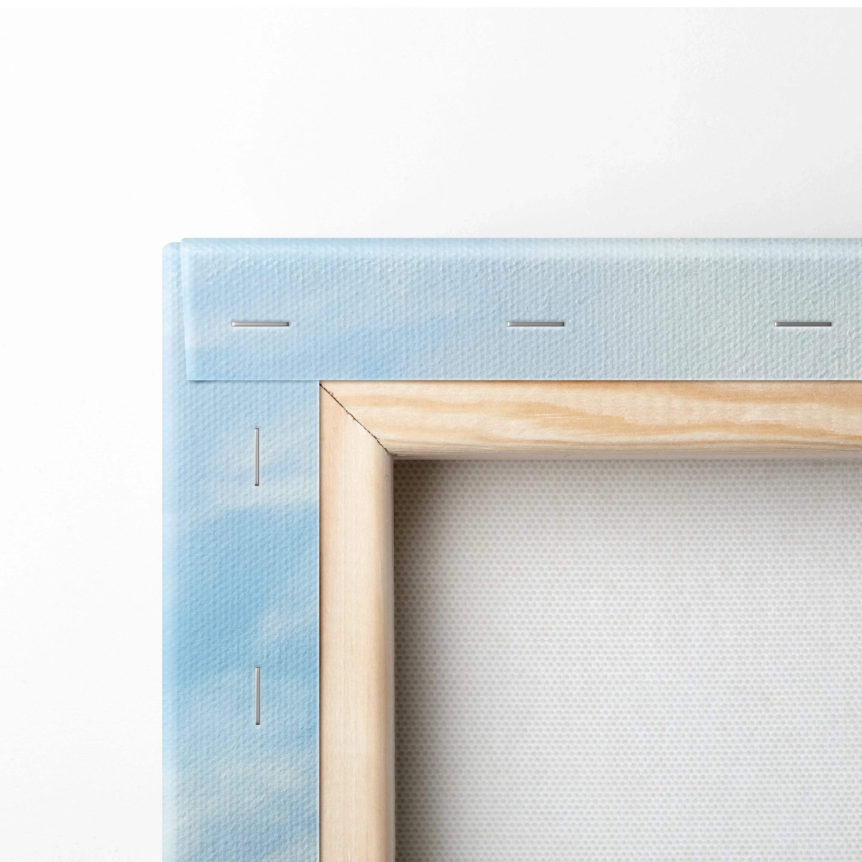 Close-up of wooden frame corner and blue sky canvas texture on stretched wall art.