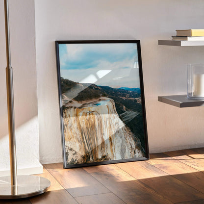 Vertical mountain landscape poster with blue sky and rocky cliffs, framed wall art.
