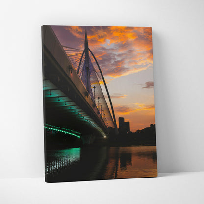 Canvas wall art featuring a modern bridge at sunset with vibrant orange sky and city skyline reflections.