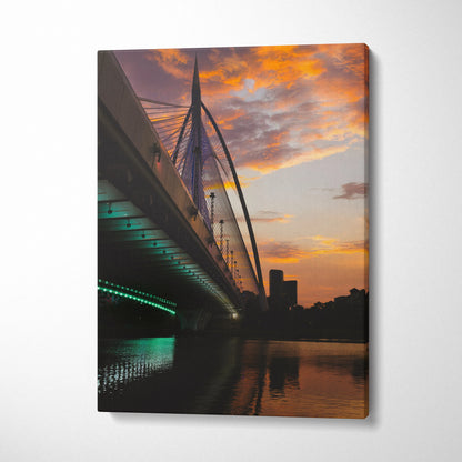 Vertical canvas wall art of city skyline at golden sunset with illuminated bridge over river.