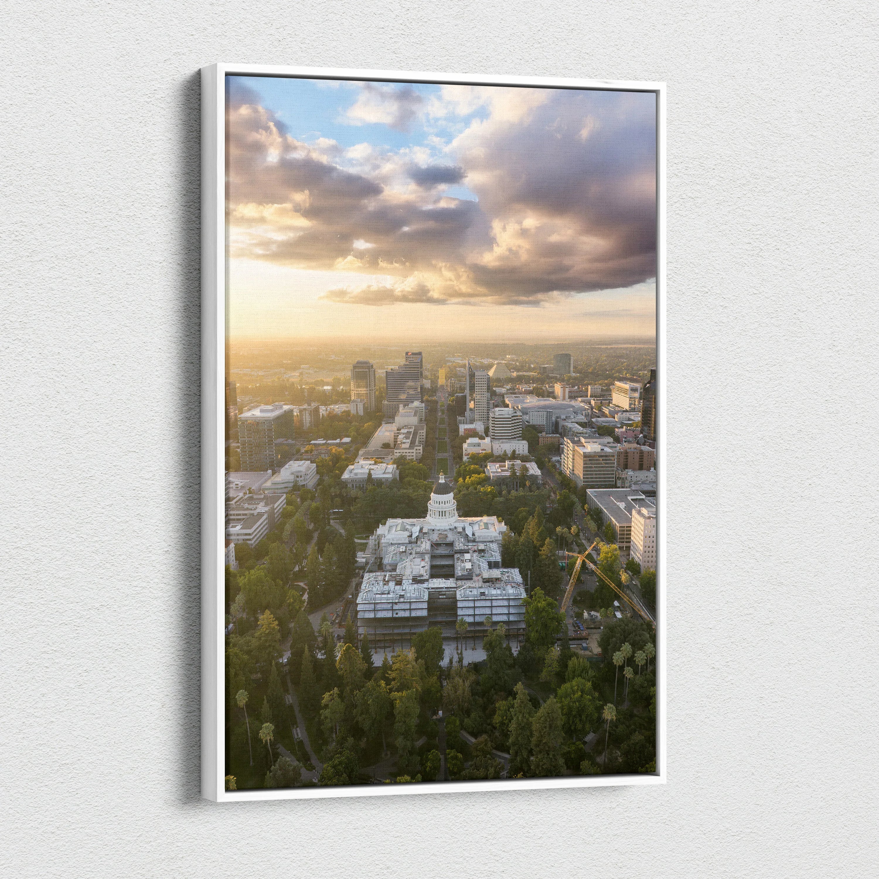 Vertical canvas wall art featuring a city skyline at sunset with dramatic clouds and warm light.