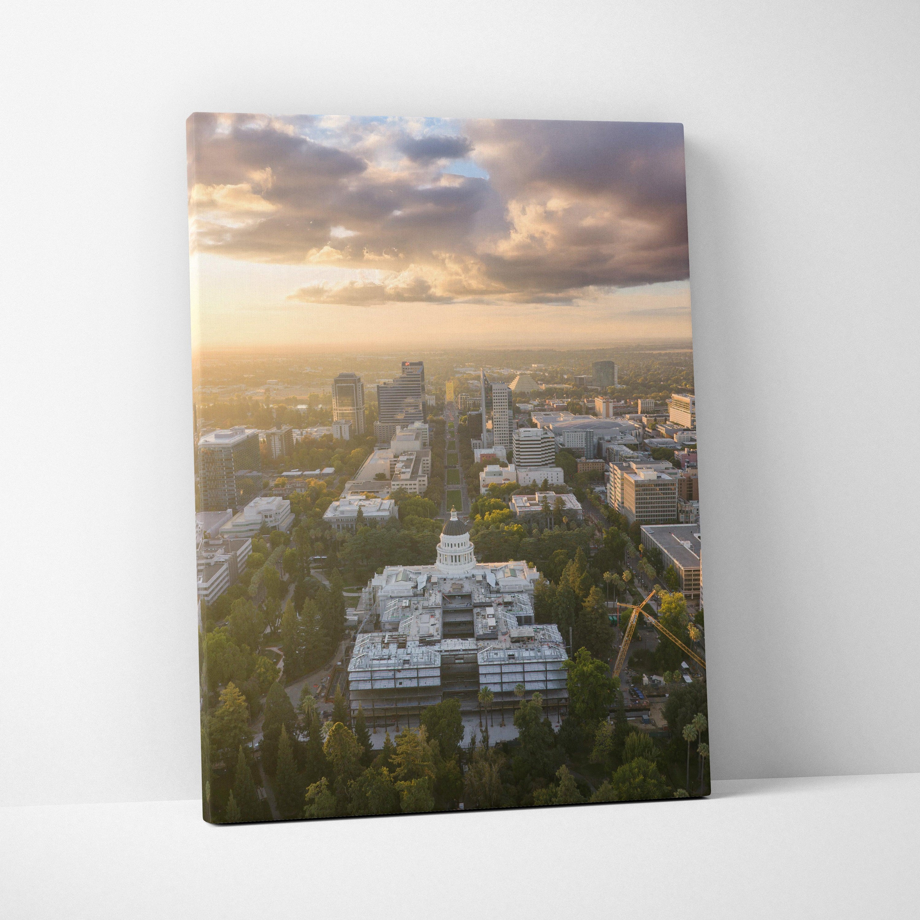Vertical canvas wall art featuring a city skyline at sunset with glowing clouds and urban buildings.
