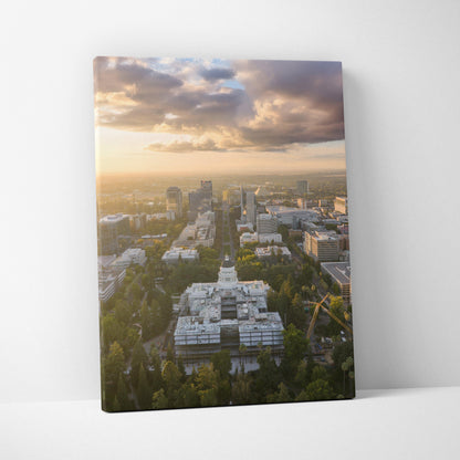 Vertical canvas wall art featuring a city skyline at sunset with glowing clouds and urban buildings.
