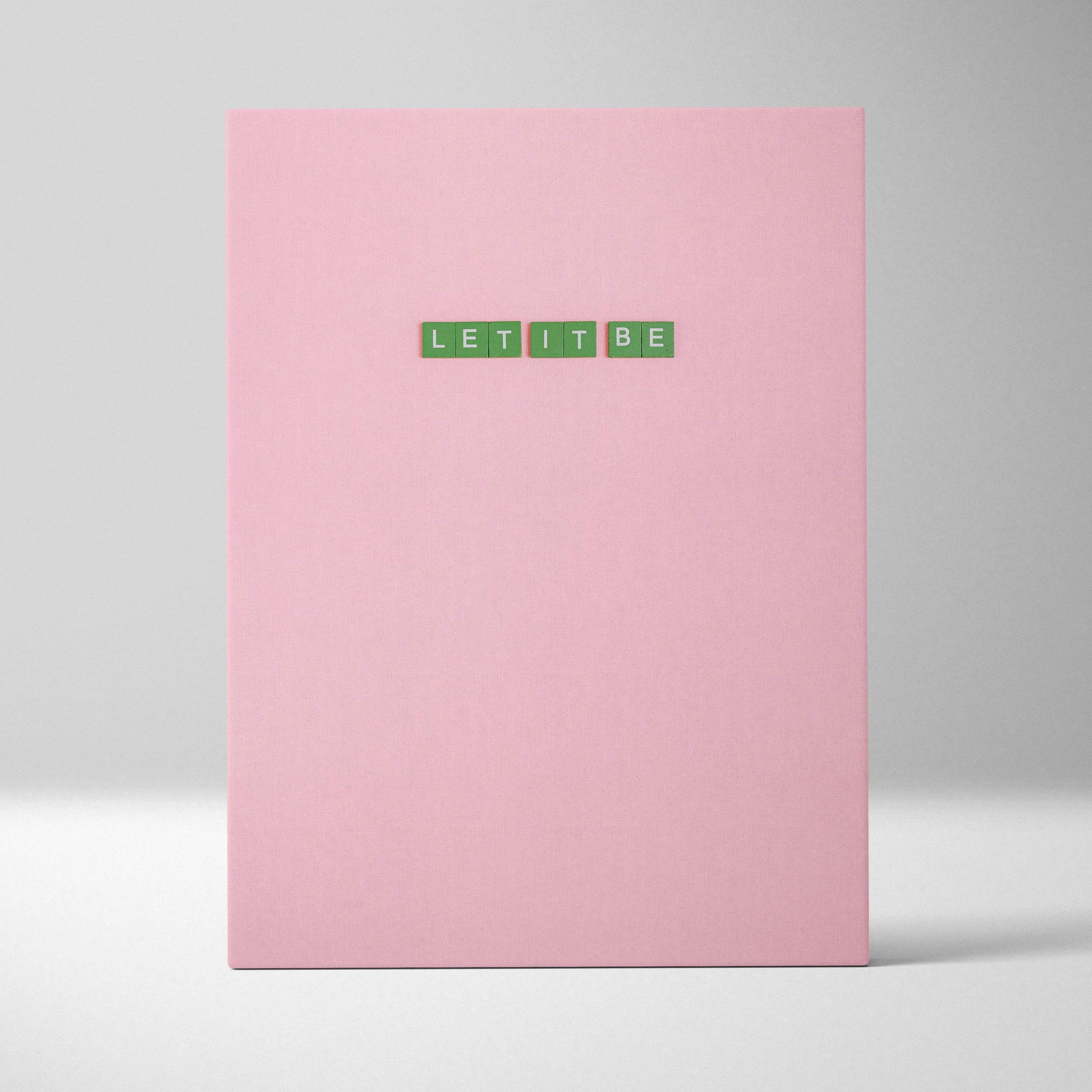 Pink hardcover notebook with green Let It Be tile letters on cover