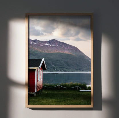 Vertical wall art poster featuring a red cabin by a lake with a majestic mountain backdrop under cloudy skies.